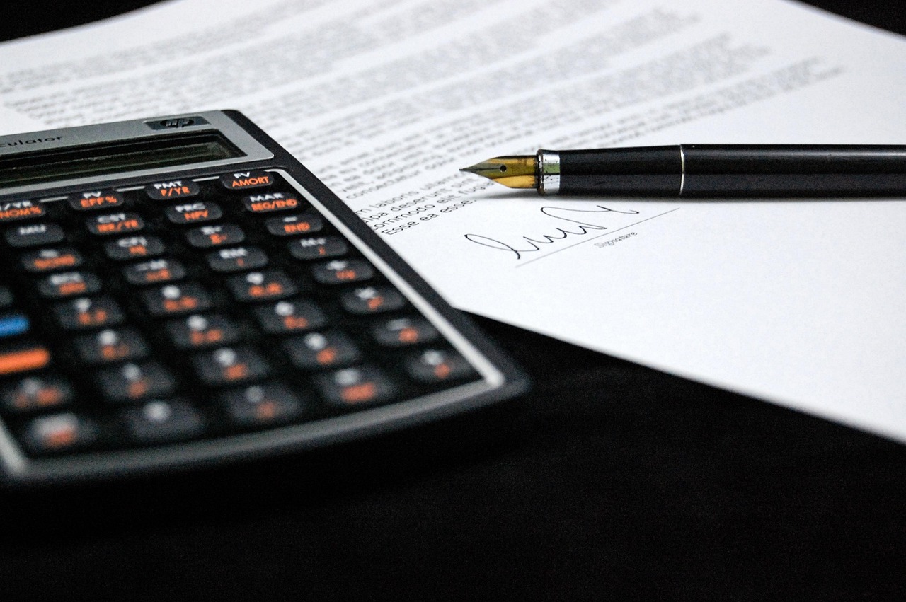 Calculatrice posée à côté d'un document signé avec un stylo plume