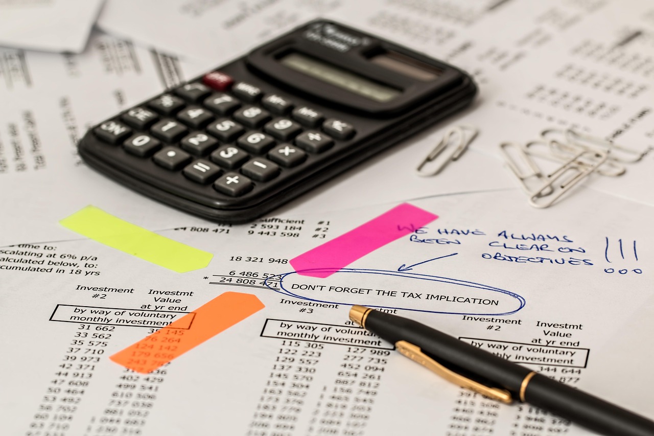 Calculatrice, documents financiers et stylo pour calculer des frais et performances