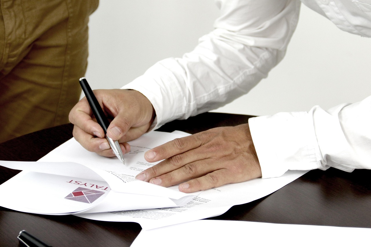 Personne en train de signer un document contractuel, stylo en main