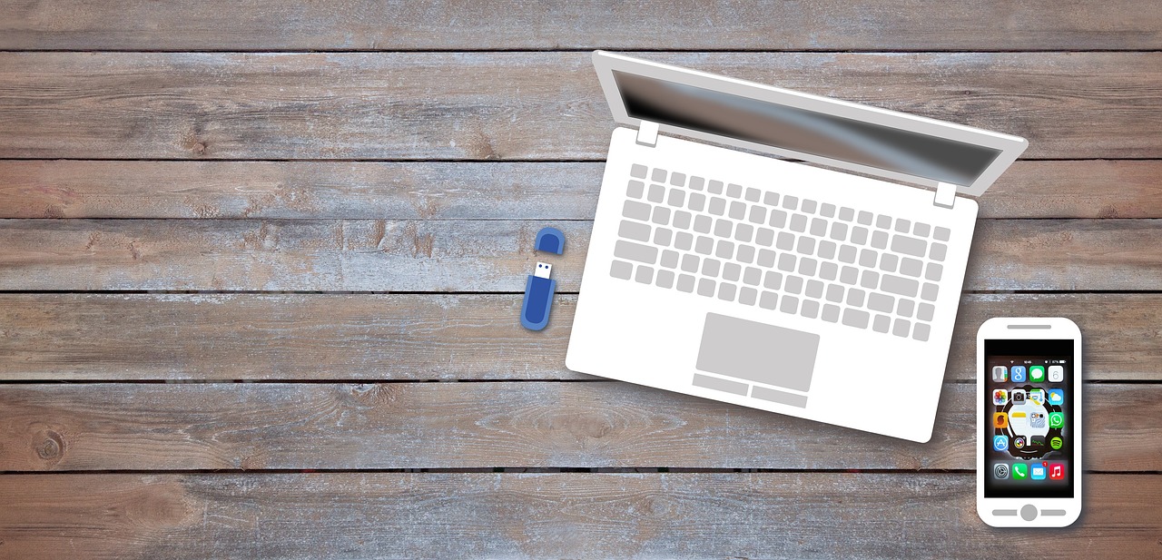 Ordinateur portable, clé USB et smartphone sur un bureau en bois, vue de dessus