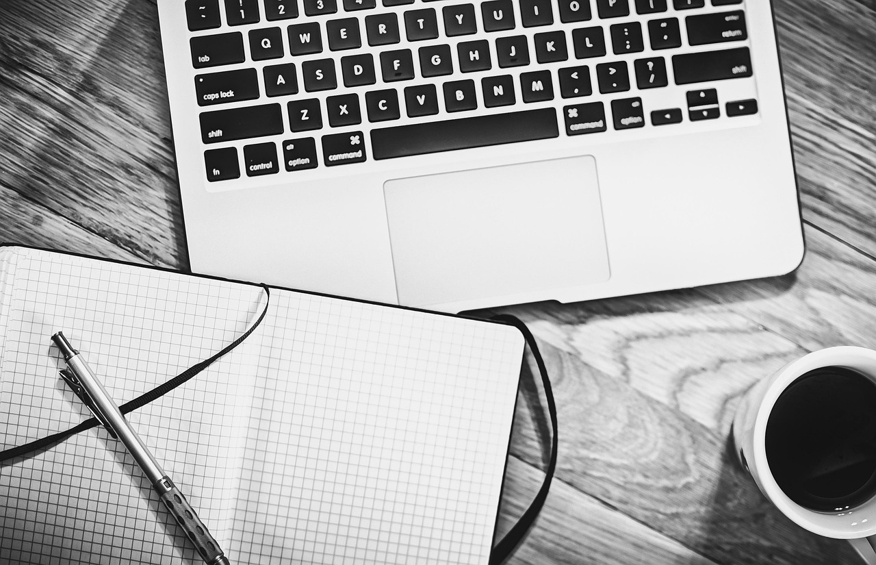 Ordinateur portable, carnet de notes, stylo et tasse de café sur un bureau