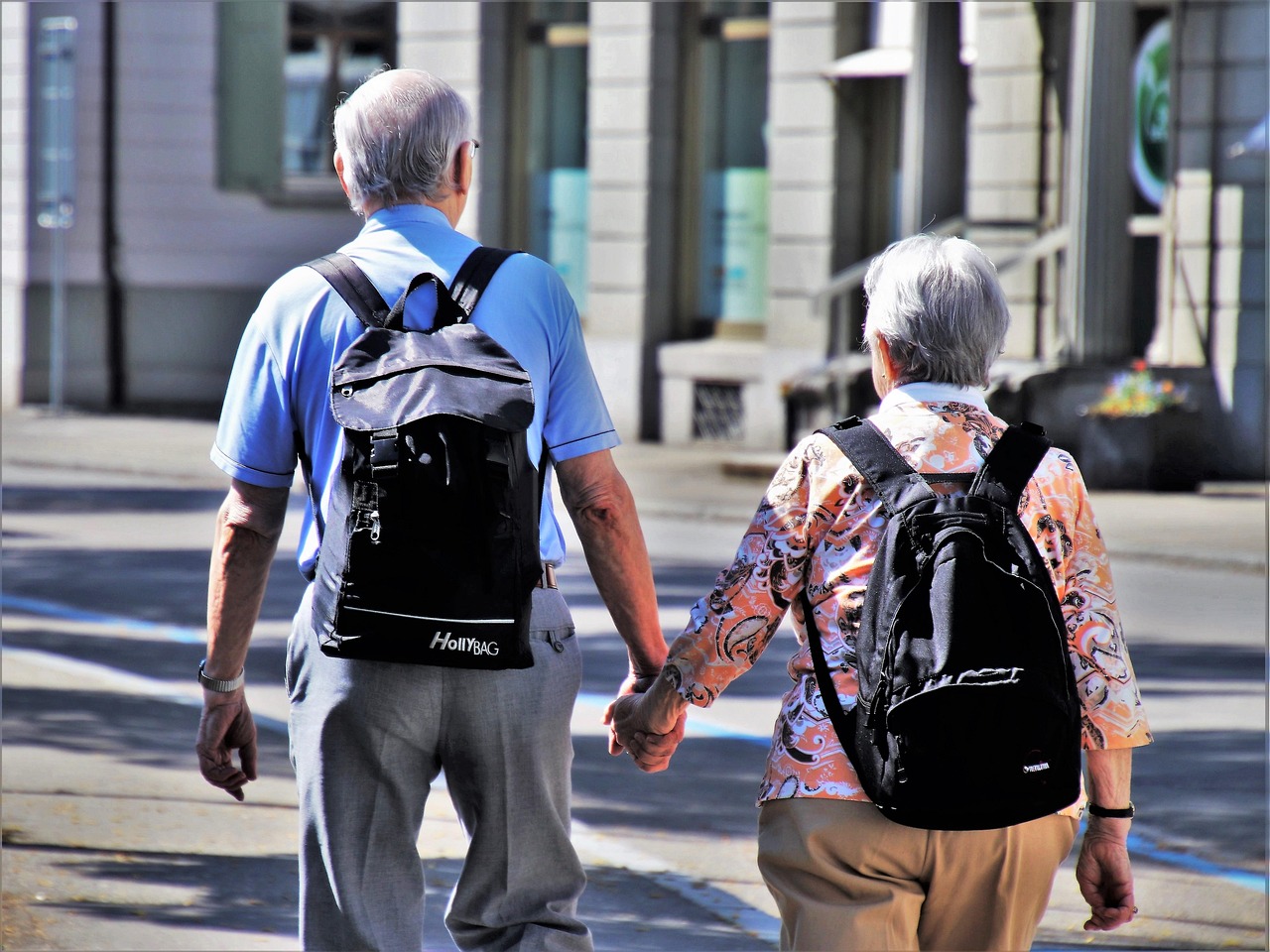 Couple de personnes âgées se tenant la main en se promenant dans une rue