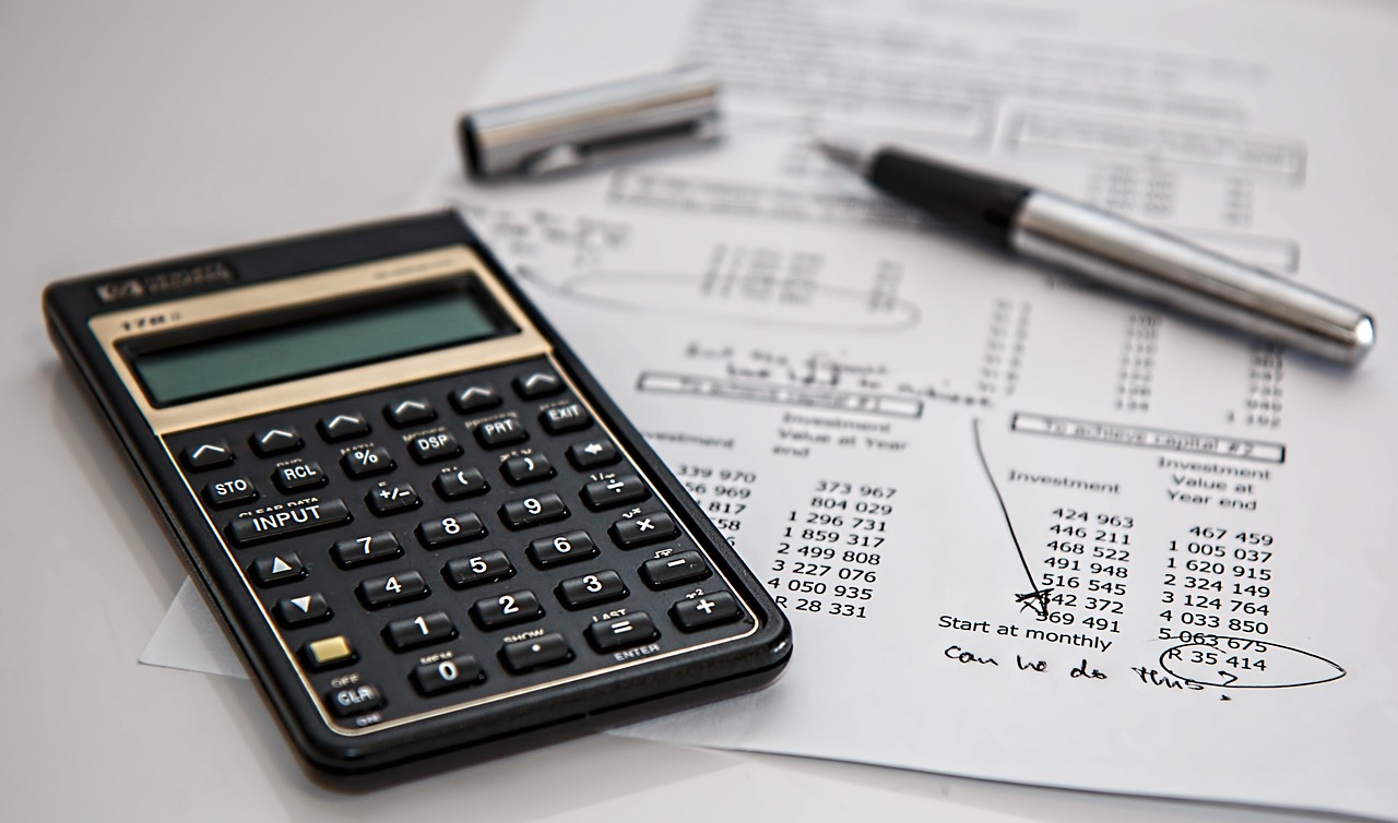 Calculatrice posée sur des documents financiers, avec un stylo