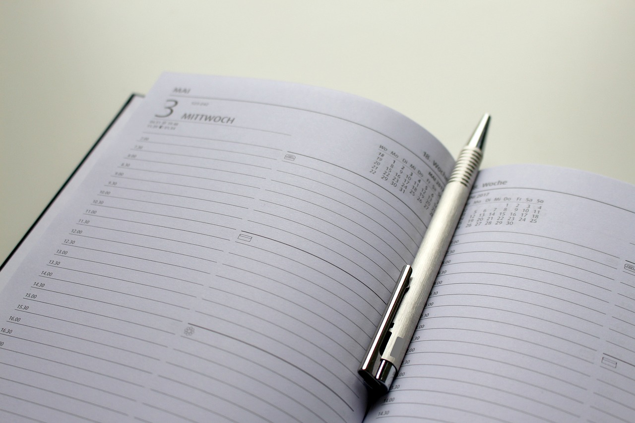 Agenda ouvert avec un stylo posé dessus sur un bureau