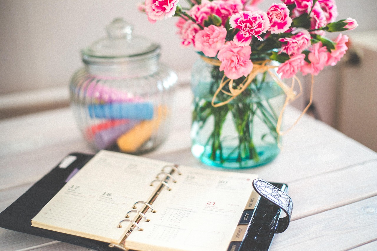 Agenda organiseur ouvert sur une table avec des fleurs en arrière-plan