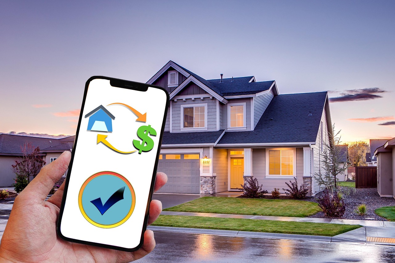 Main tenant un smartphone affichant une application de banque en ligne devant une maison