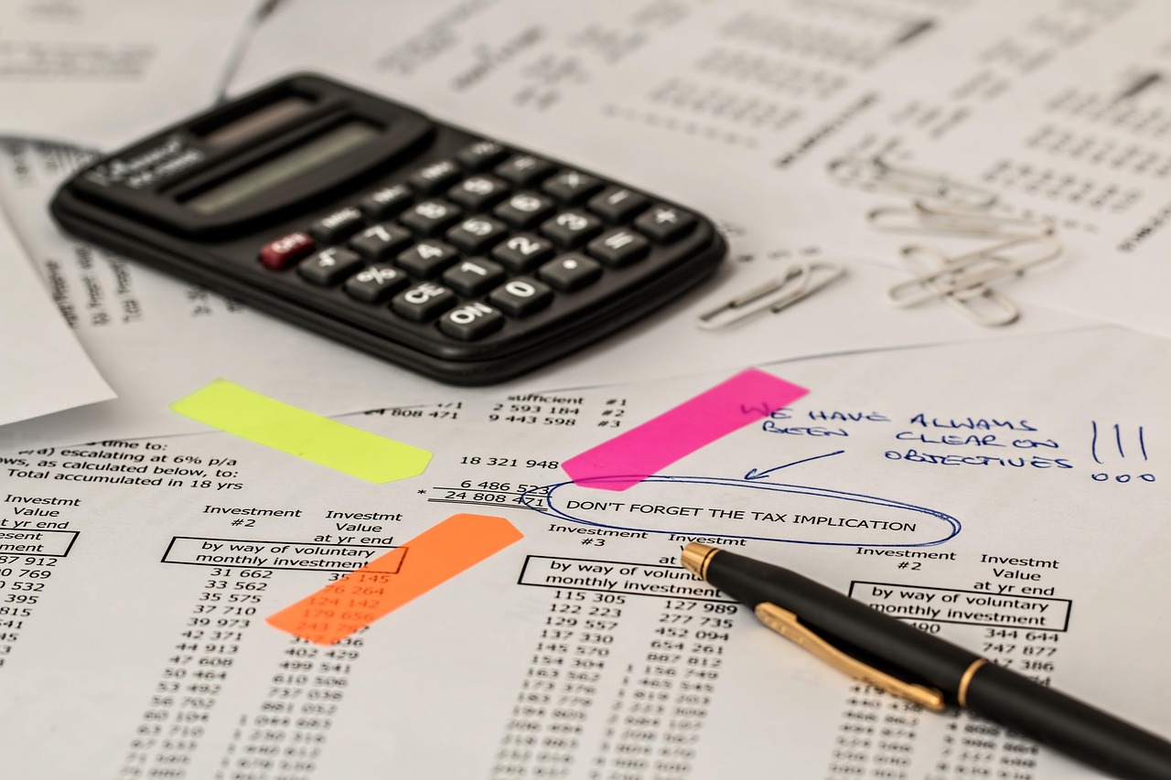 Calculatrice posée sur des documents financiers avec surligneurs colorés