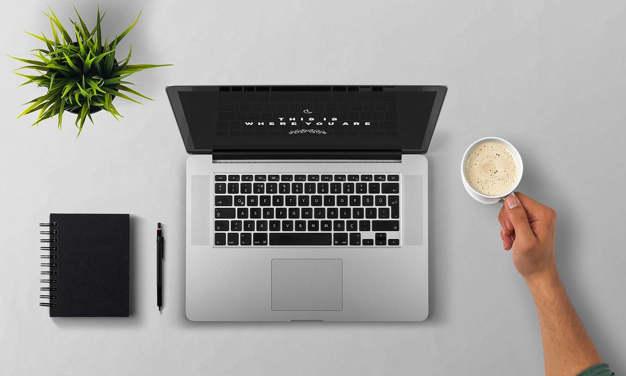 Ordinateur portable, carnet et tasse de café vus de dessus sur un bureau